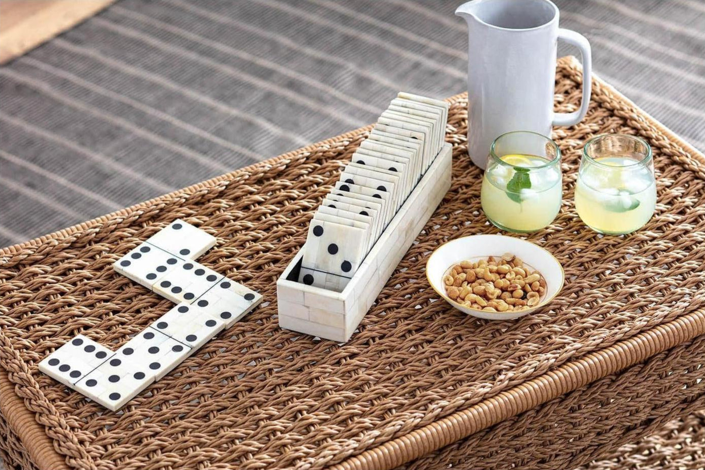 Dominoes set on a woven mat with glasses and a pitcher