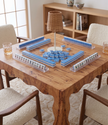 Wooden table with a game of tiles and chairs around it in a room.